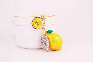 Detail view of a lemon keychain with sparkling rhinestones and a gold-plated enamel finish