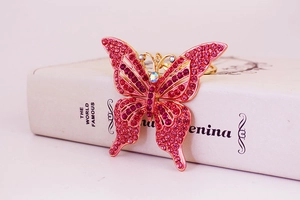 Gros plan d'un porte-clés papillon rose orné de strass posé sur un décor de livre