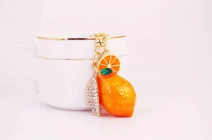 Detailed view of an orange lemon keychain with rhinestones and golden lobster clasp