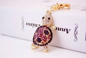 Detailed view of turtle keychain with purple and white crystals on golden base