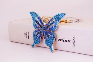 Gros plan détaillé du pendentif papillon en strass bleu et violet avec finition dorée