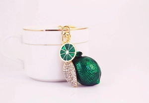 Macro view of rhinestone-studded lemon pendant keychain with green enamel fruit charms