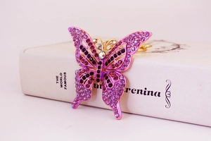 Détail macro du porte-clés papillon avec strass violets et métal doré brillant