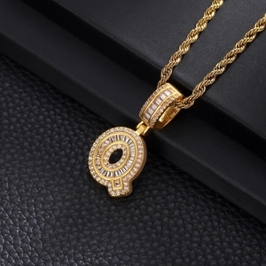 Macro shot of iced out gold letter Q pendant with baguette zircons on twist chain