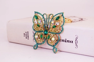 Détail du porte-clés papillon doré orné de pierres vertes et de strass brillants
