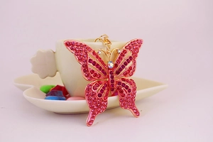 Détail du porte-clés papillon avec cristaux roses et base dorée sur une tasse