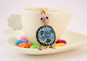 Detailed close-up of crystal turtle keychain with blue gradient rhinestones on white cup