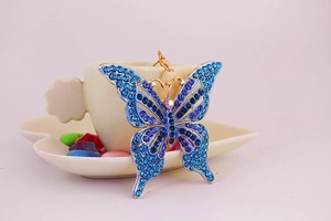 Détail du porte-clés papillon en cristal bleu et violet sur le bord d'une tasse