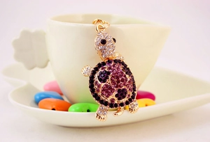 Macro detail of turtle keychain with purple, black and clear rhinestones on gold alloy