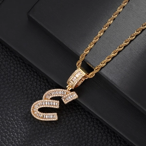 Macro detail of iced-out gold letter B pendant with cubic zirconia and rope chain