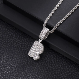 Vue macro du pendentif lettre R glacé avec des zircons pavés brillants sur chaîne