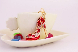 Vue macro d'un porte-clés escarpin rouge à strass suspendu au bord d'une tasse blanche