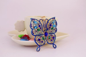 Détail d'un porte-clés papillon en strass bleus avec motifs de cristal et dorure