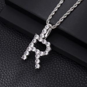 Macro shot of silver hip hop pendant with cubic zirconia letter R on rope chain