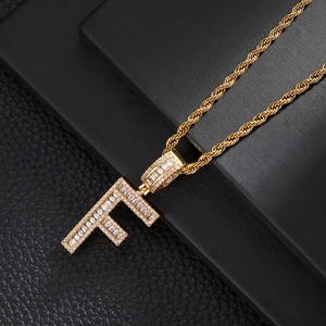 Close-up of golden letter F pendant with cubic zirconia inlay on thick rope chain