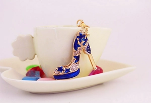 Détail d'un porte-clés escarpin émaillé bleu avec cristaux accroché à une tasse à café