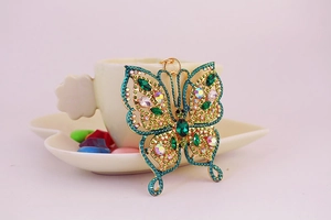 Détail du porte-clés papillon en émeraude avec placage doré et strass étincelants