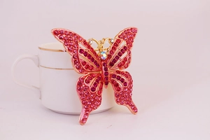 Détail d'un porte-clés papillon avec strass roses accroché sur une tasse blanche