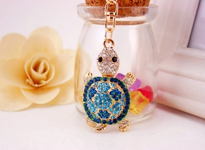 Close-up of sparkling blue rhinestones on gold turtle keychain with floral decor