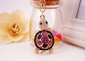 Detailed view of turtle keychain with purple and black rhinestones on a golden base