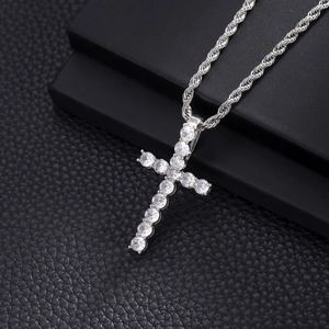Close-up of a silver cross pendant with clear cubic zirconia on a thick rope chain