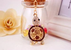 Close-up of golden turtle keychain featuring sparkling white and brown rhinestone crystals