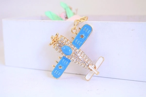Makroaufnahme vom Kampfjet-Schlüsselanhänger mit Strass, blauem Emaille und Goldclip
