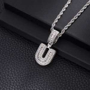 Détail macro du pendentif lettre U en argent glacé avec zircons et chaîne de type corde
