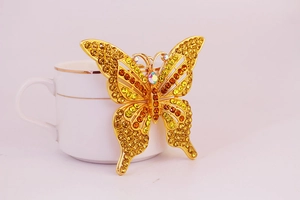 Gros plan du pendentif papillon doré avec des strass et des cristaux dégradés jaunes