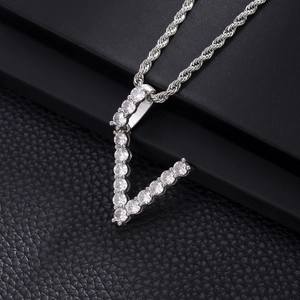 Macro detail of V-shaped silver pendant with cubic zirconia on black leather