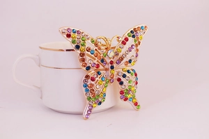 Gros plan d'un porte-clés papillon doré avec strass colorés sur une tasse en porcelaine