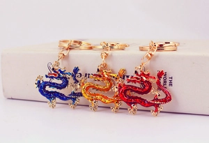 Detailed macro view of colorful enamel dragon keychains in blue, yellow, and red with gold clasps