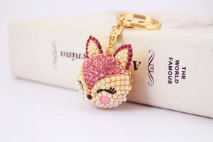 Détail du porte-clés renard avec strass roses et perles blanches sur cadre doré
