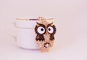 Detailaufnahme der goldenen Eule mit glitzernden Strasssteinen an einer weißen Kaffeetasse