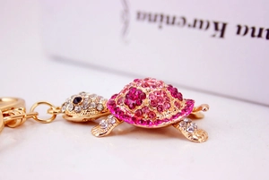 Macro shot of rhinestone turtle keychain with vibrant pink and rose crystals on gold base