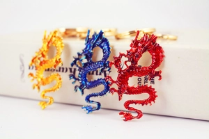 Detailed close-up of three traditional Chinese dragon keychains in red, blue, and gold colors