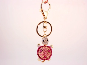 Detailed macro view of turtle keychain with pink and clear crystals on gold metal