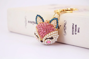 Vue macro d'un porte-clés renard avec cristaux roses et perles sur livre blanc