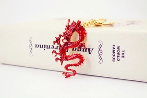 Detail view of the red Chinese dragon keychain on a white book showing metal textures