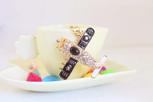 Macro detail of golden fighter jet keychain with sparkling rhinestones and black wings
