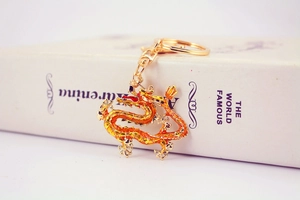 Close-up of golden dragon keychain with orange enamel detail and rotating clasp