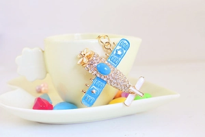 Detail of aircraft keychain with blue enamel, white rhinestones and golden metal finish