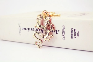 Close-up of a golden Chinese dragon keychain with detailed scales on a white book
