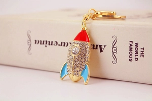 Détail du porte-clés fusée dorée avec strass brillants et pointe en émail rouge