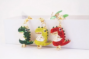 Detailed close-up of rhinestone dinosaur keychains in green, yellow, and red colors