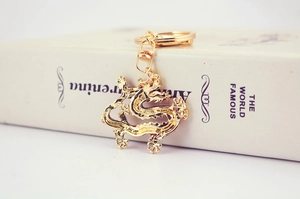 Detailed view of the golden Chinese dragon keychain with intricate scales on a book