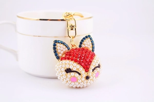 Détail d'un porte-clés renard avec strass rouges et perles sur un clip doré