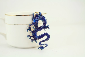 Detailed view of a blue enamel dragon keychain hanging on a white porcelain cup rim