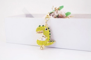 Detail of a sparkling rhinestone dinosaur keychain with yellow crystals on a gift box background