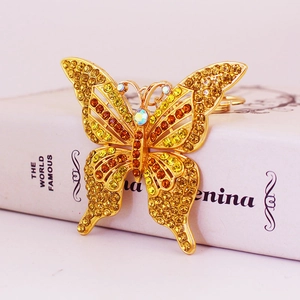 Porte-clés papillon doré avec des strass jaunes et oranges sur un fond blanc élégant